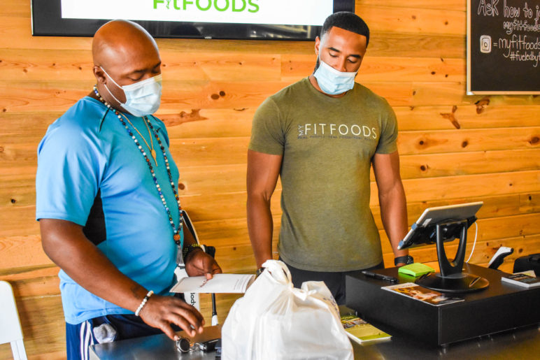 image of MyFitFoods customer and employee standing at the store checkout counter