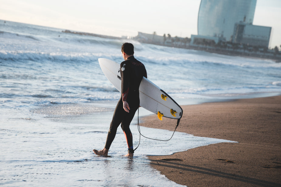 Image of surfer walking into the water on the beach