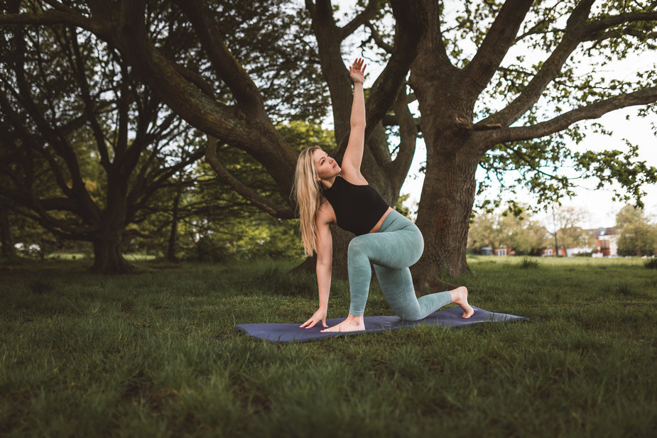image of person doing yoga on a mat under a tree